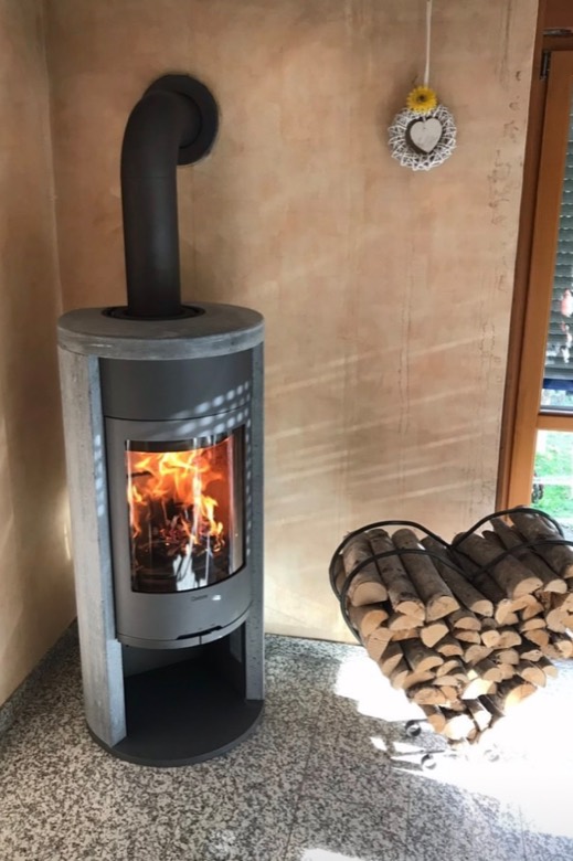 Kaminofen mit Speckstein, daneben ein Holzhalter in Herzform